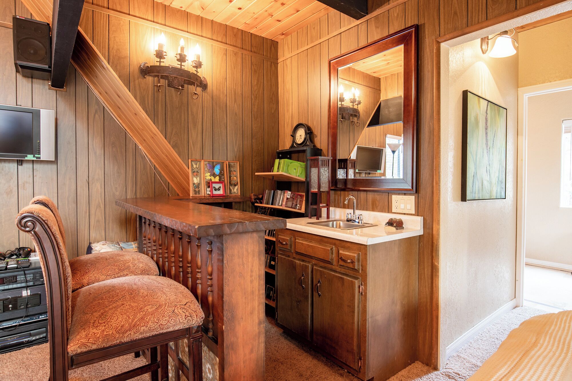 A wooden interior with a dining area, a kitchen with a sink, and a large mirror.