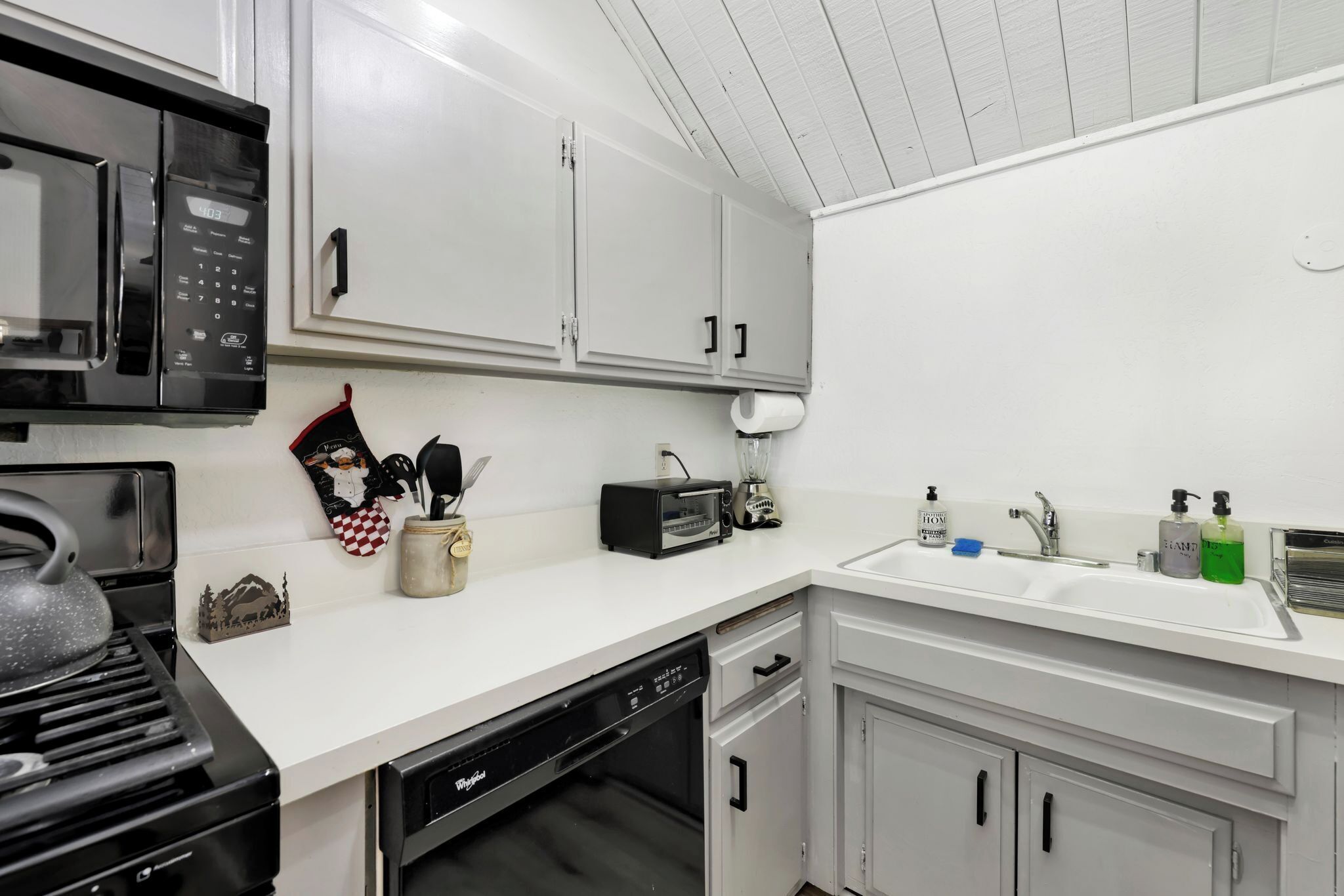 Une cuisine moderne avec des meubles blancs, un four à micro-ondes, un grille-pain et un lave-vaisselle.