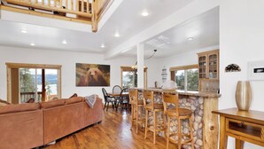 A spacious living area with a wooden floor, a brown leather sofa, and a stone accent wall. - Cozy Lakeview Hideaway #2261 (Fawnskin)