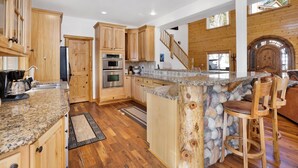 A spacious kitchen with wooden cabinets, a granite countertop, and a stone island. - Cozy Lakeview Hideaway #2261 (Fawnskin)