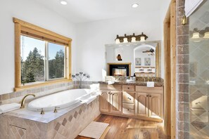 Ein geräumiges Badezimmer mit einer großen freistehenden Badewanne, einem Holzausleger und einem Spiegel sowie einem Kamin.