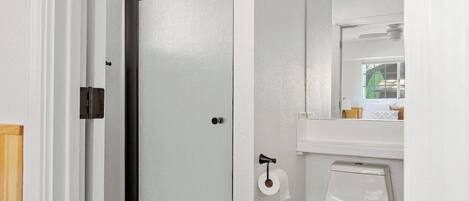 Ein Badezimmer mit Toilette, Duschkabine und Spiegel über dem Waschbecken.