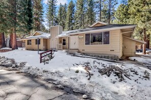 Une cabane avec une façade en bois, une cheminée et une véranda.