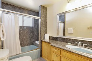 Une salle de bain avec une baignoire, des toilettes, un lavabo et un grand miroir.