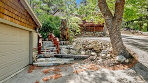 Una casa con un garage, una scala in pietra e un grande albero.