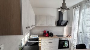 Een moderne keuken met een inbouwoven, een koffiezetapparaat en een spoelbak.