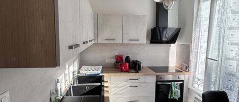 A modern kitchen with a built-in oven, a coffee maker, and a sink.