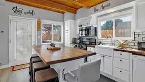 A modern kitchen with white cabinets, a wooden countertop, and a built-in oven.