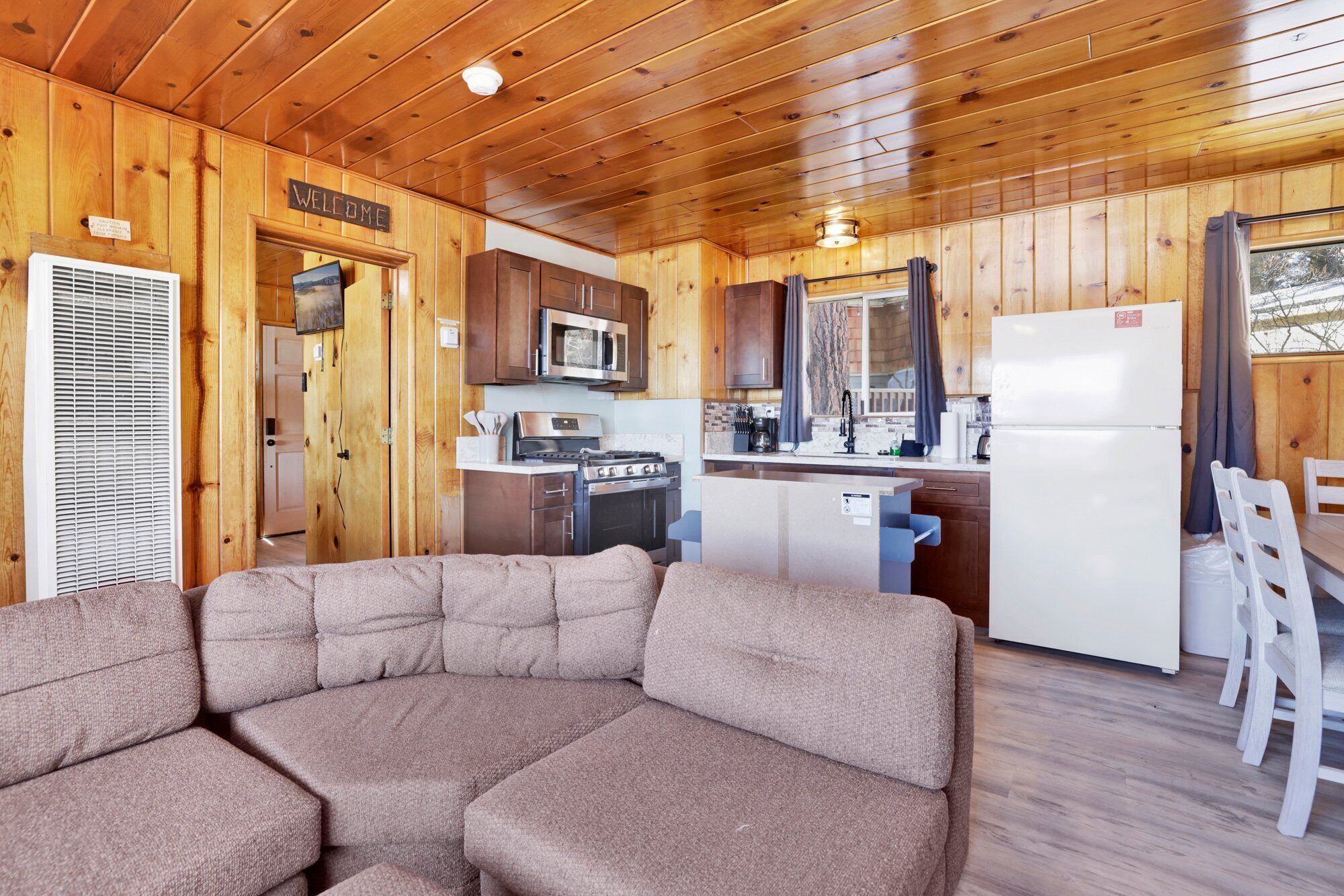A cozy cabin-style room with a wooden interior, a kitchenette, a sofa, and a dining area.