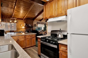 A kitchen with wooden cabinets, a stove, a refrigerator, and a dining area with a table and chairs.
