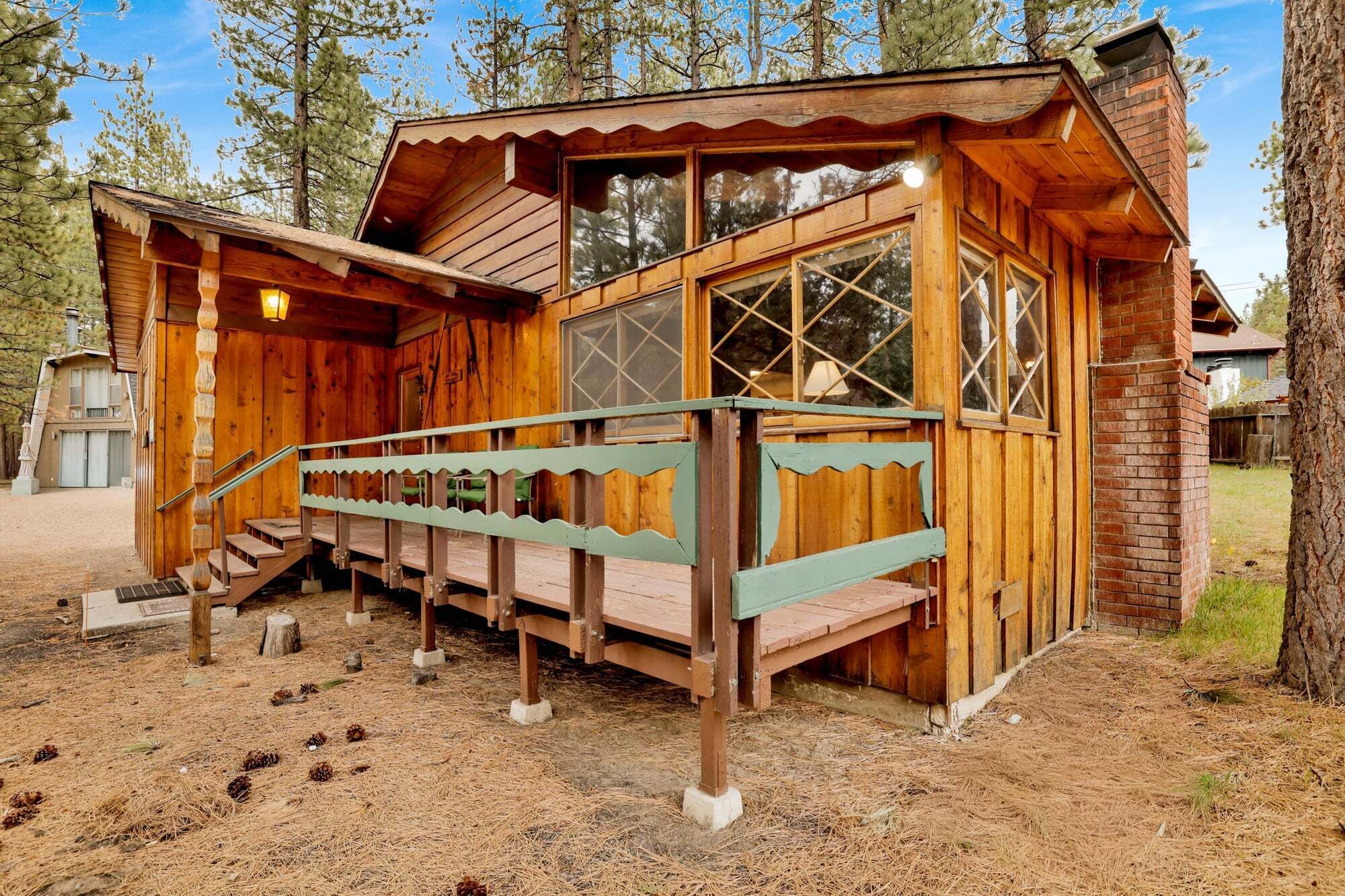 A wooden cabin with a porch, a staircase, and a chimney.