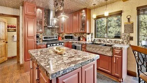 A spacious kitchen with granite countertops, a large island, and a stone backsplash. - HOW Sweet IT IS #1531 (Big Bear Lake)