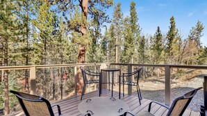 A deck with a round table and six chairs, surrounded by a wooden railing, overlooking a forested area. - HOW Sweet IT IS #1531 (Big Bear Lake)