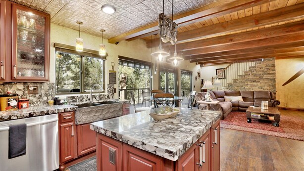 A spacious kitchen with granite countertops, a large island, and a dining area with a stone fireplace. - HOW Sweet IT IS #1531 (Big Bear Lake)