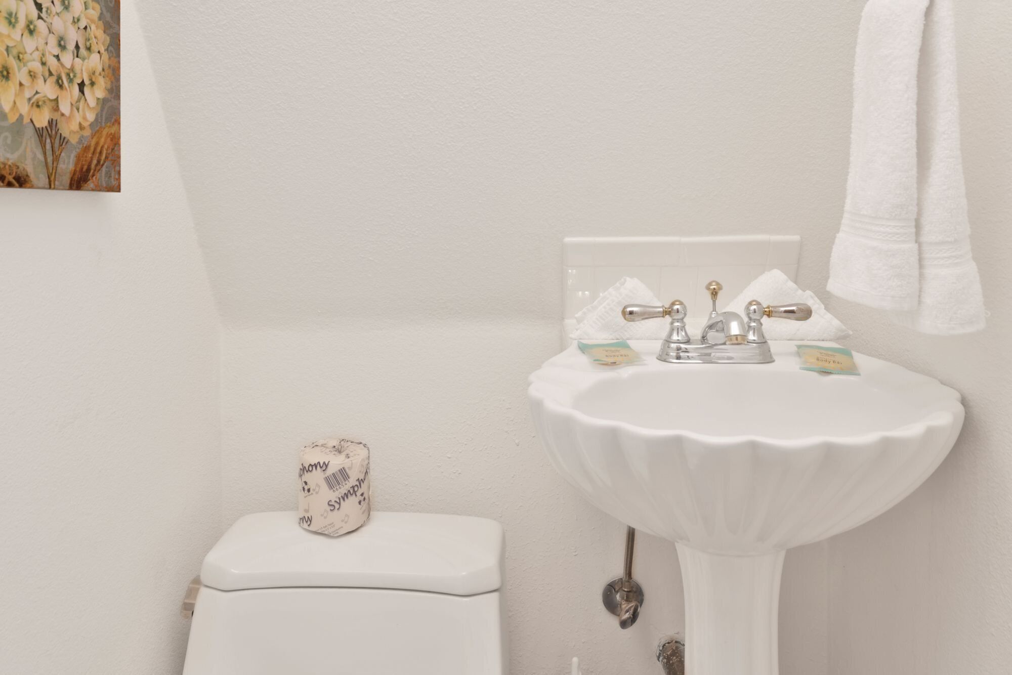 A bathroom with a white sink, a toilet, and a towel hanging on the wall.