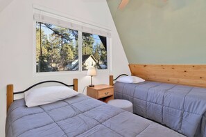 A bedroom with two beds, a window with a view of trees, and a wooden headboard. - THE Pyramid IN BIG Bear #2124 (Big Bear City)