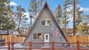 Una casa triangular con una valla de madera al frente.