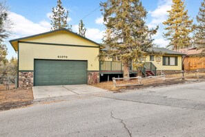 A yellow building with a green garage door, number 41070, next to a tree and a small house.