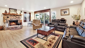 A spacious living room with a stone fireplace, leather sofas, and a dining area. - A Hidden Asset #2379 (Big Bear Lake)