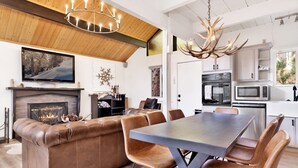 A modern living room with a fireplace, leather sofa, and a dining area with a large table and chairs.