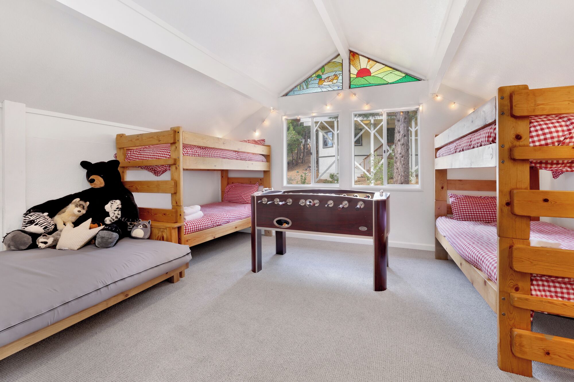 A room with bunk beds, a small table, and a window with a view of trees.