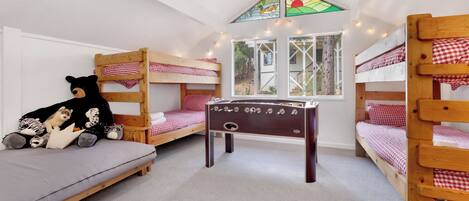 A room with bunk beds, a small table, and a window with a view of trees.