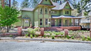 A two-story house with a green exterior, a front porch, and a brick foundation. - Apres SKI Haus #2201 (Big Bear Lake)
