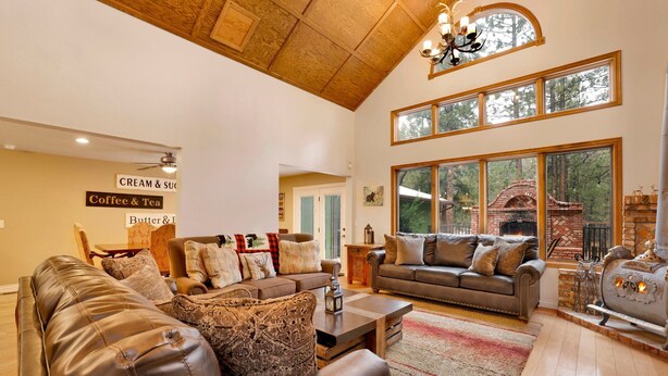 A spacious living room with leather sofas, a fireplace, and large windows offering a view of the outdoors. - Apres SKI Haus #2201 (Big Bear Lake)