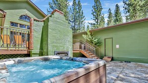 A hot tub in a backyard with a wooden deck and a green house. - Apres SKI Haus #2201 (Big Bear Lake)