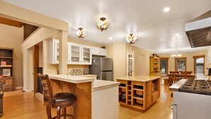 A spacious kitchen with wooden cabinets, a central island, and a dining area with a table and chairs. - Apres SKI Haus #2201 (Big Bear Lake)