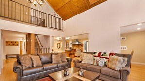 A spacious living area with two leather sofas, a coffee table, and a staircase leading to an upper level. - Apres SKI Haus #2201 (Big Bear Lake)
