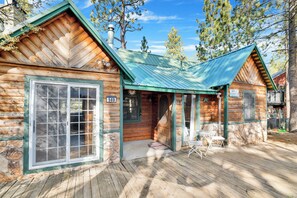 A log cabin with a green metal roof, stone foundation, and a wooden deck. - Temple Lake Views#2298 (Big Bear Lake)