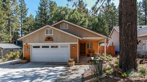A two-story log cabin with a garage, surrounded by a forest.