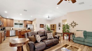 A spacious living room with a leather sofa, a coffee table, and a dining area with wooden cabinets and a refrigerator.