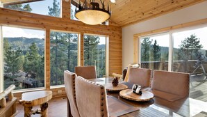 A cozy cabin interior with wooden walls and large windows offering a forest view. - Silver TIP Chalet #2141 (Big Bear Lake)