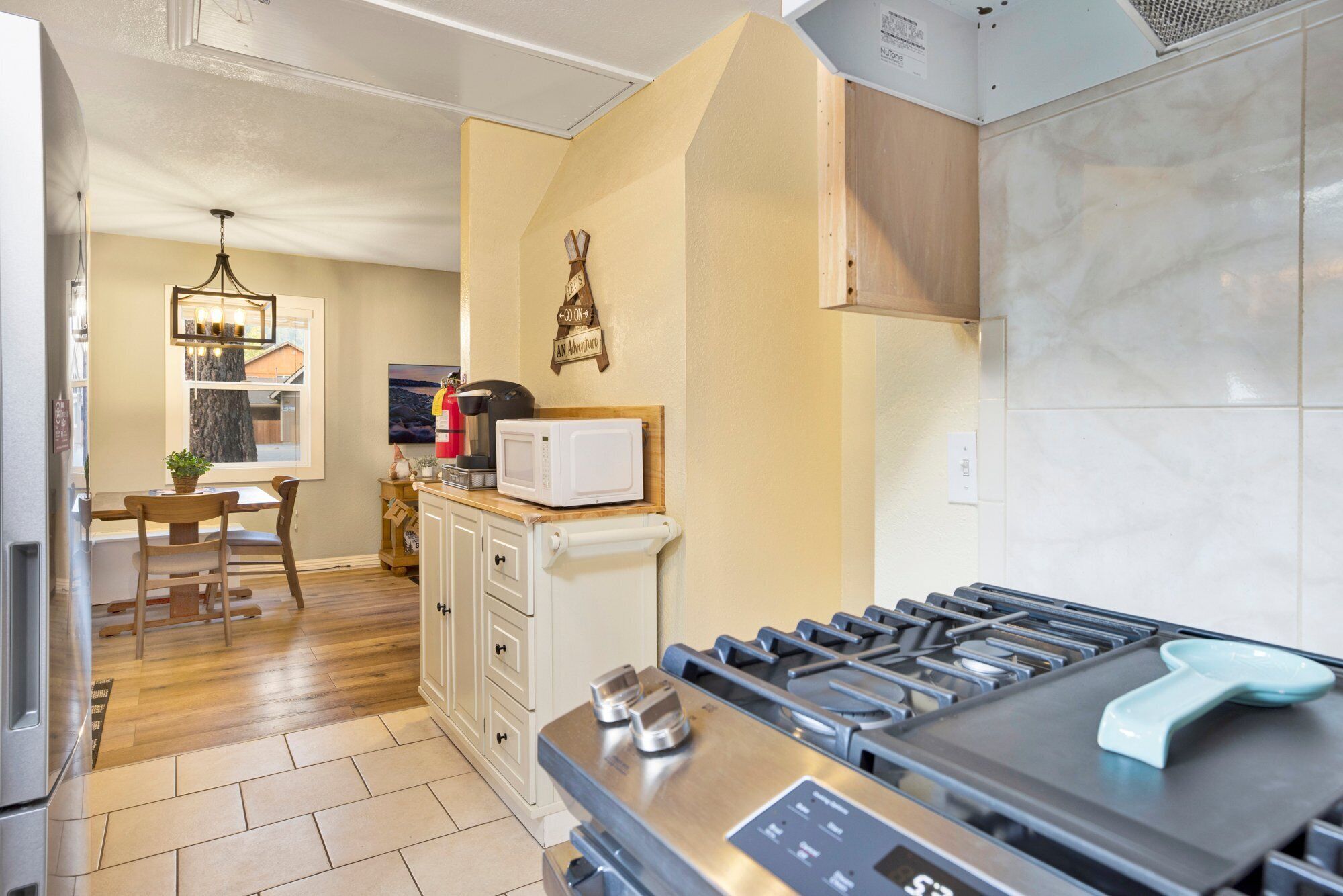 A modern kitchen with a gas stove, microwave, and wooden cabinets.