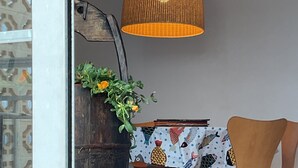 Ein Essbereich mit einem Tisch, der mit einer tischdecke mit Fischmuster bedeckt ist, einem Holzstuhl und einer hängenden Leuchte.