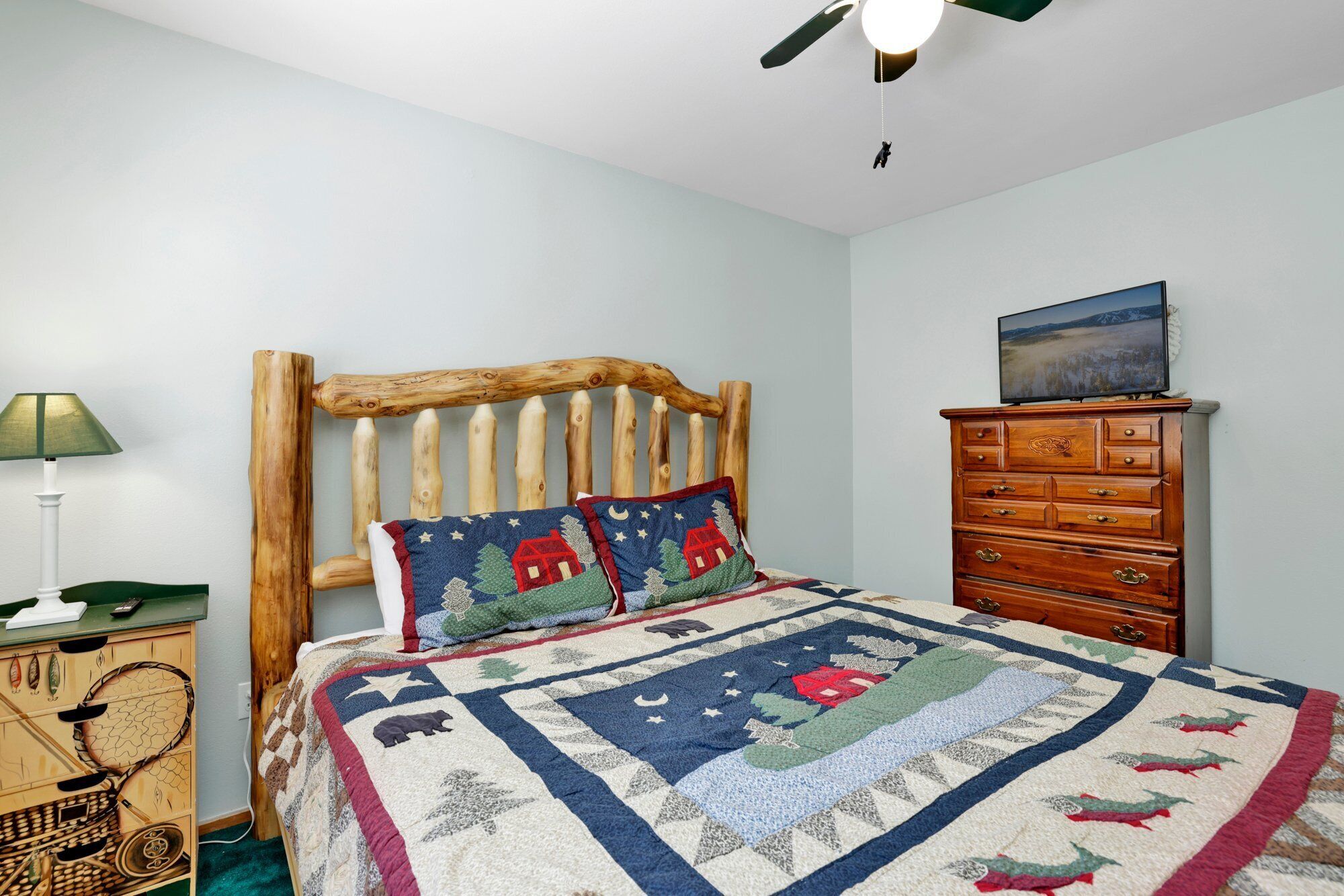 Ein Schlafzimmer mit einem hölzernen Kopfteil, einer Winter-Steppdecke, einem Schminktisch und einer Lampe.