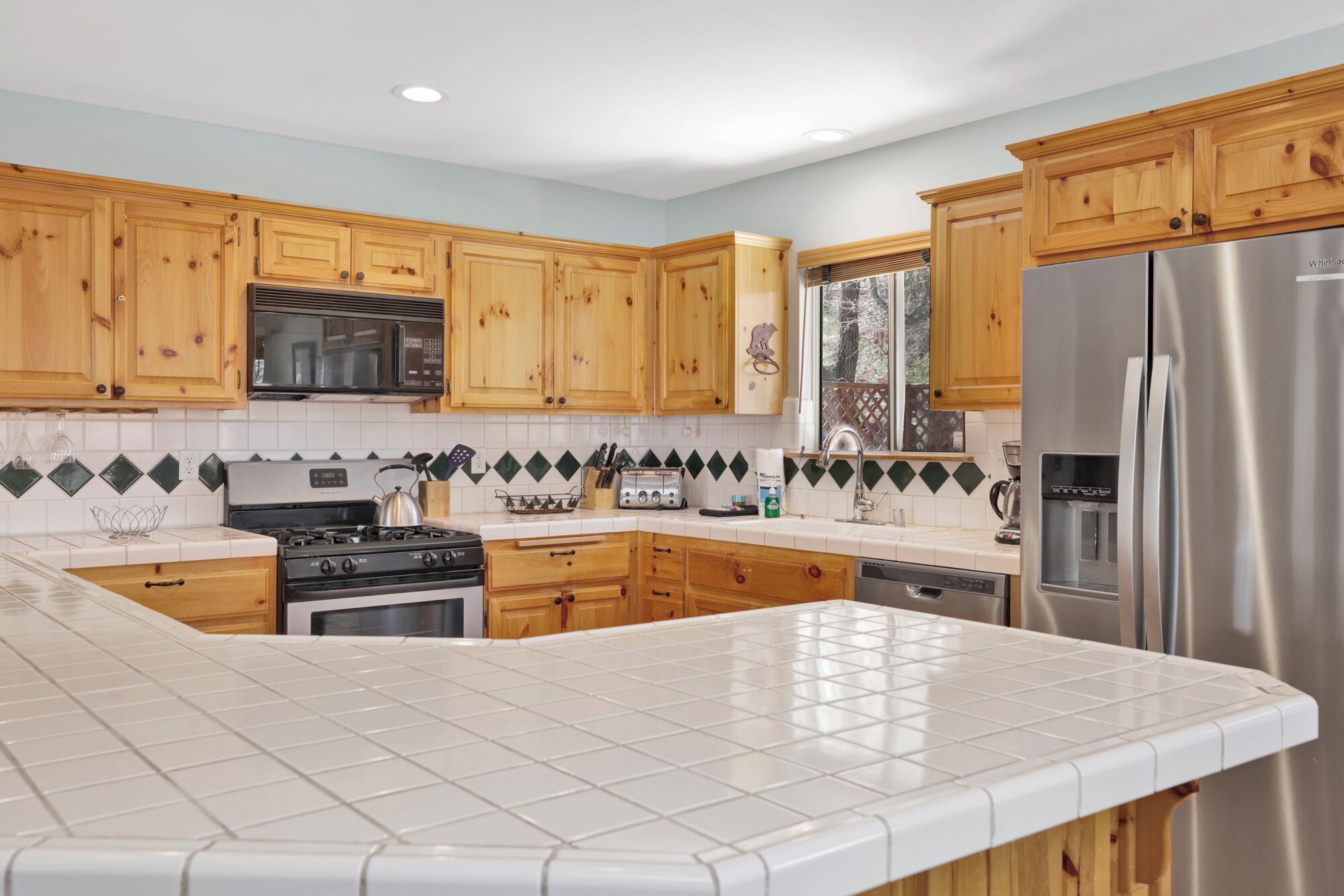 A modern kitchen with wooden cabinets, a stainless steel refrigerator, a gas stove, and a dishwasher.