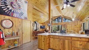 Une cabane en bois spacieuse, dotée d’une grande cuisine, d’une table à manger et d’un coin salon confortable.