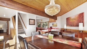 A dining area with a wooden table, chairs, and a chandelier. There is a staircase leading to another room. - THE Octagon #2394 (Big Bear City)