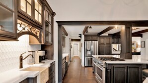 A modern kitchen with dark wood cabinetry, stainless steel appliances, and a herringbone wood floor. - Soaring Pines #2193 (Big Bear Lake)