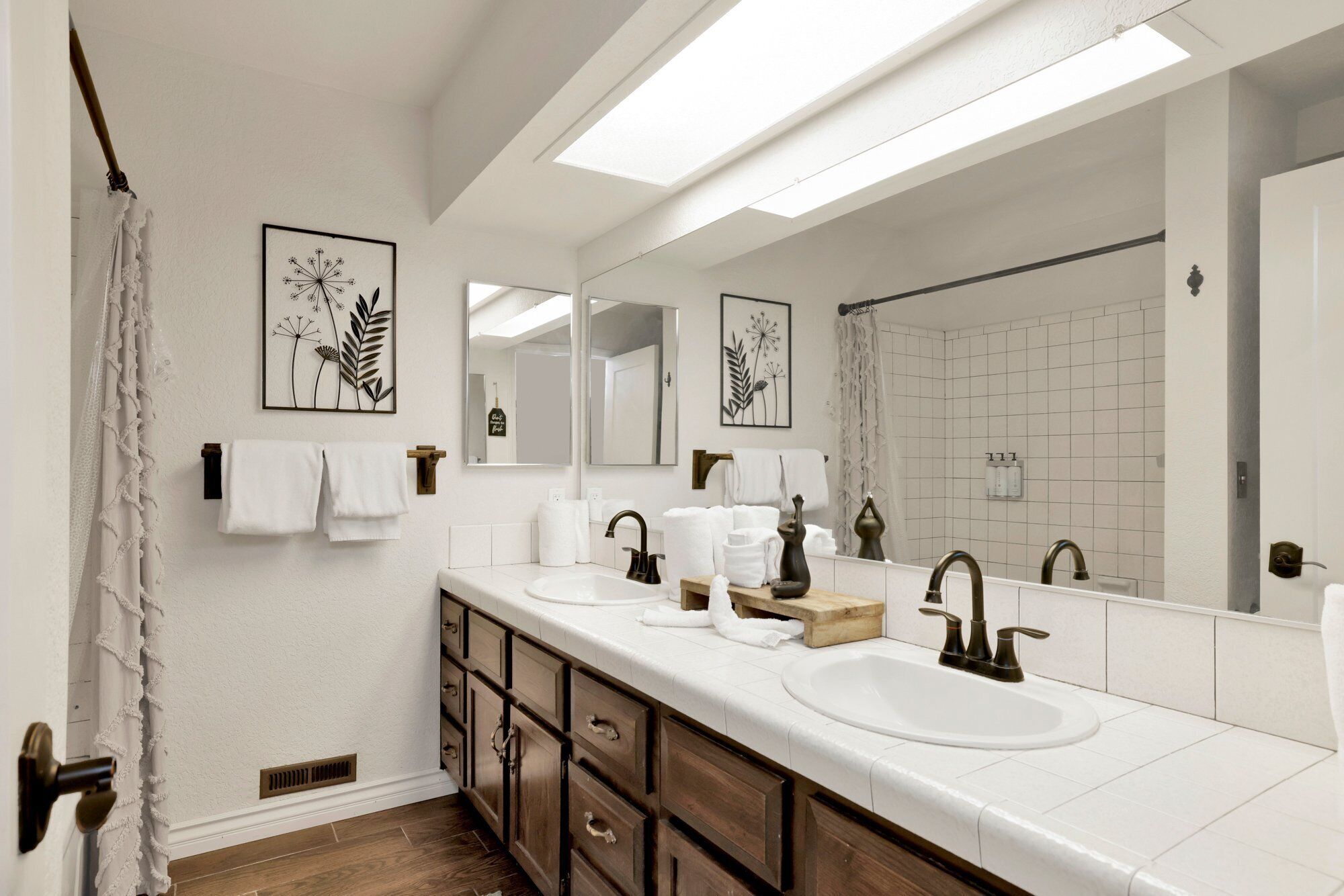 A modern bathroom with two sinks, a large mirror, and a shower area.