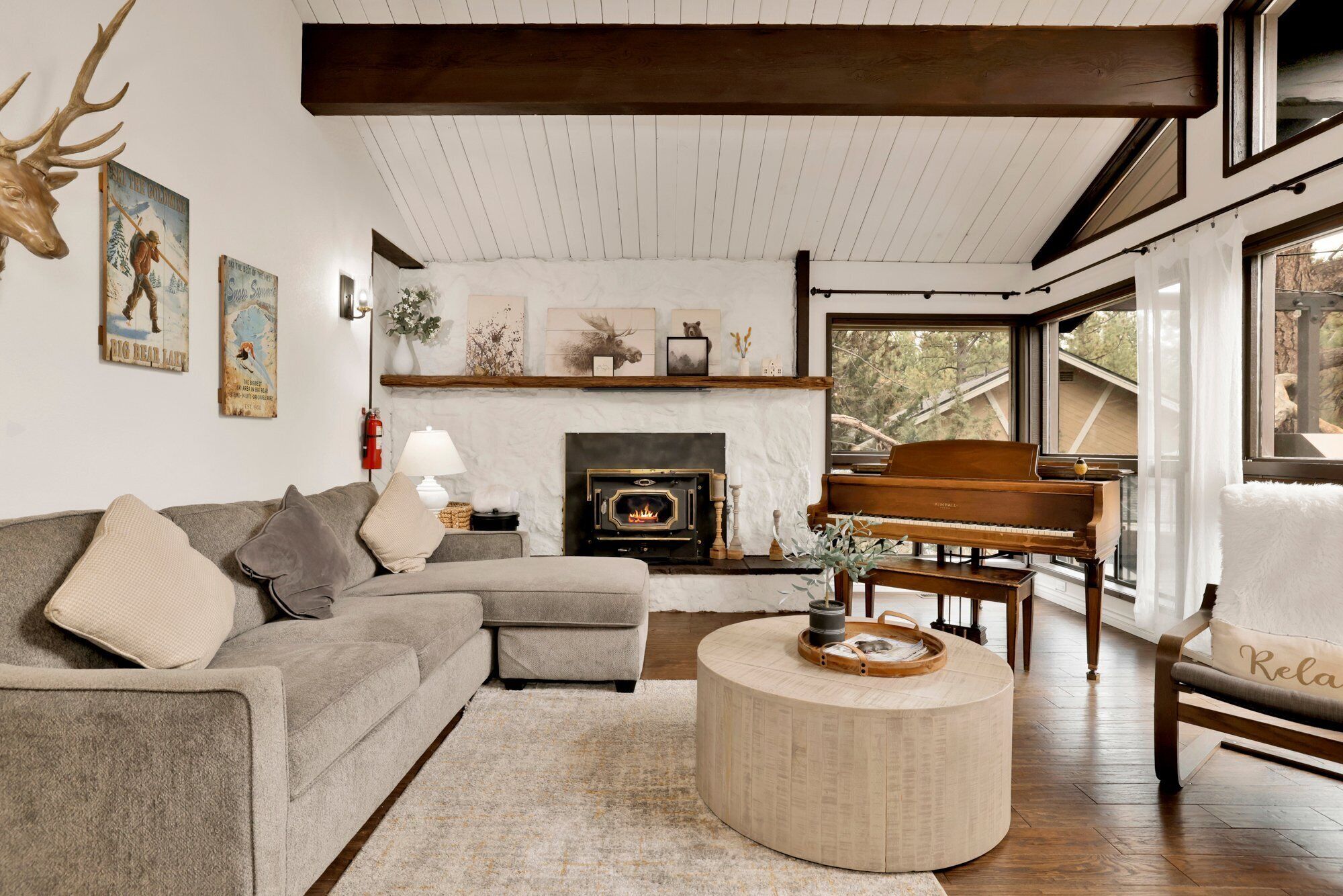 Una sala de estar acogedora con chimenea, un piano y un ventanal con vistas al exterior.