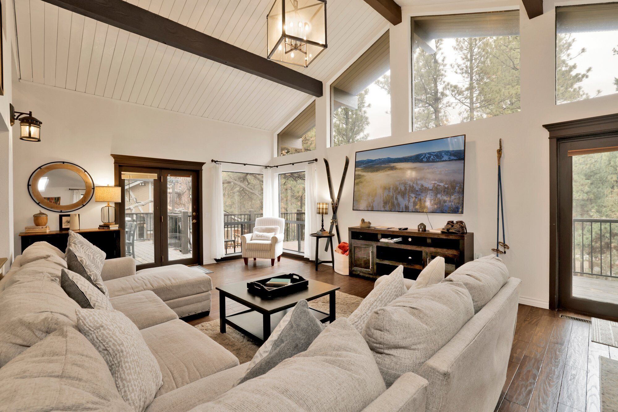 A spacious living room with a large sectional sofa, a fireplace, and a large window offering a view of the outdoors.