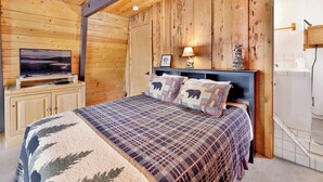 Une chambre dans une cabane en bois, avec un lit, une télévision et une table de chevet.