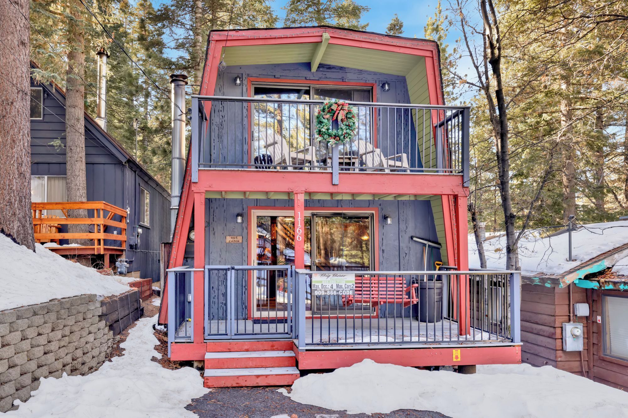 A two-story cabin with a balcony, a front porch, and a sign indicating it is a cabin.