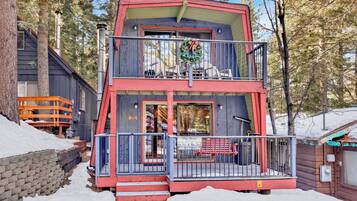 A two-story cabin with a balcony, a front porch, and a sign indicating it is a cabin.