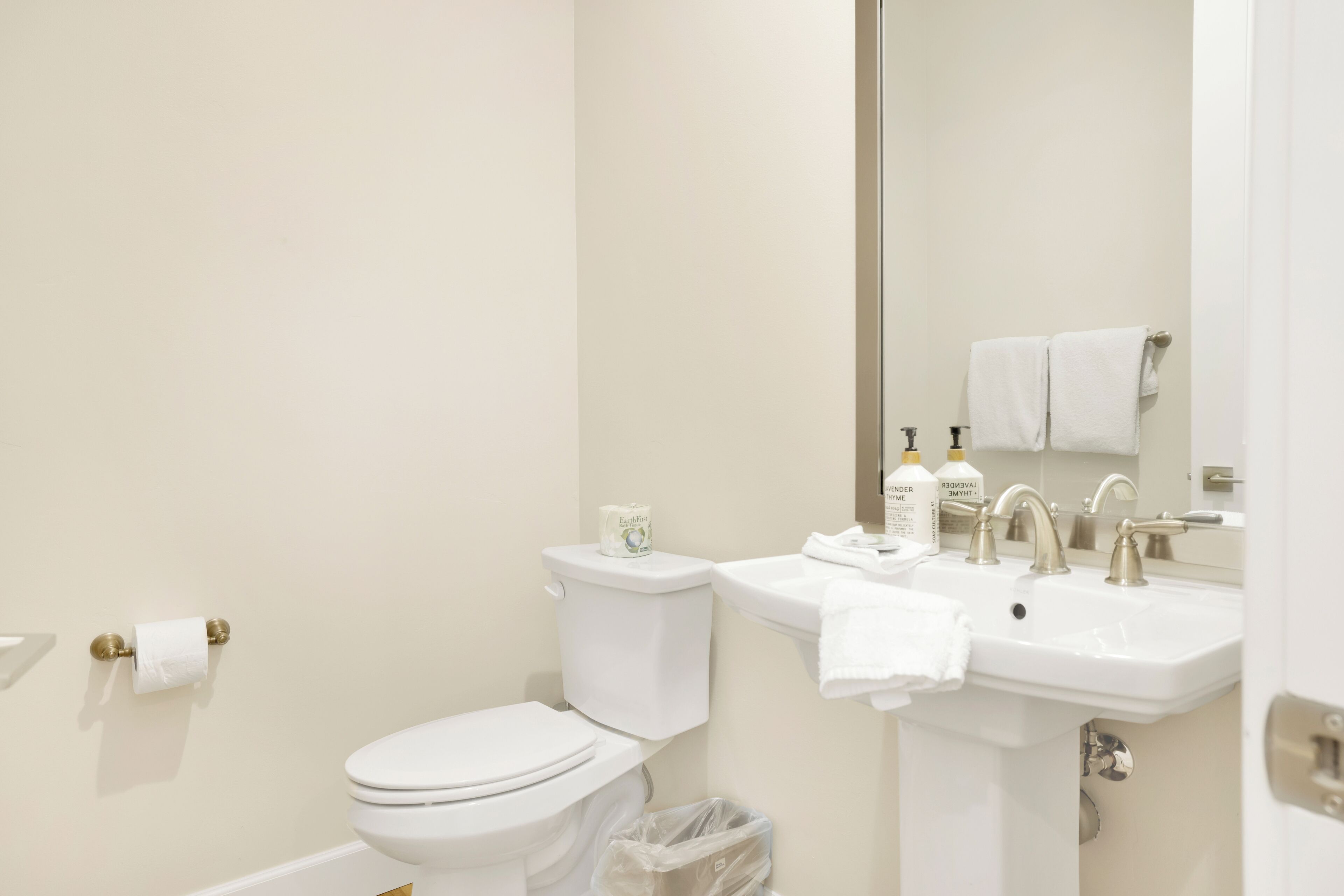 A bathroom with a toilet, sink, and mirror.