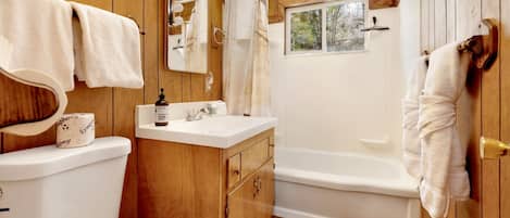 Une salle de bain aux finitions en bois, équipée de toilettes, d’un lavabo et d’une baignoire.